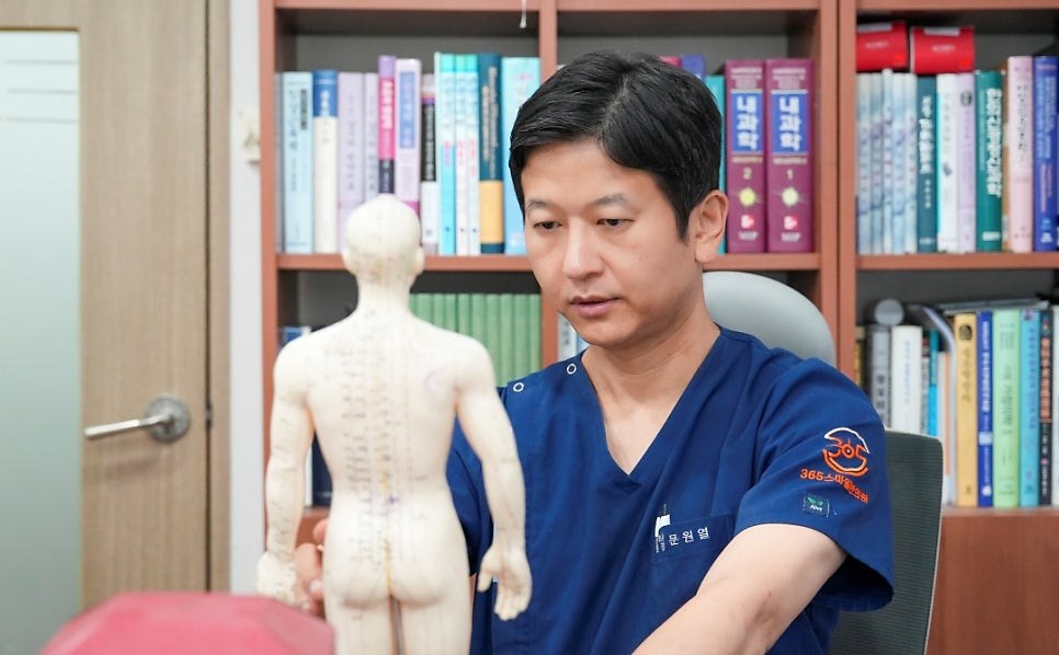 진료실에서 경혈 인체 모형을 보고 있는 문원열 대표원장